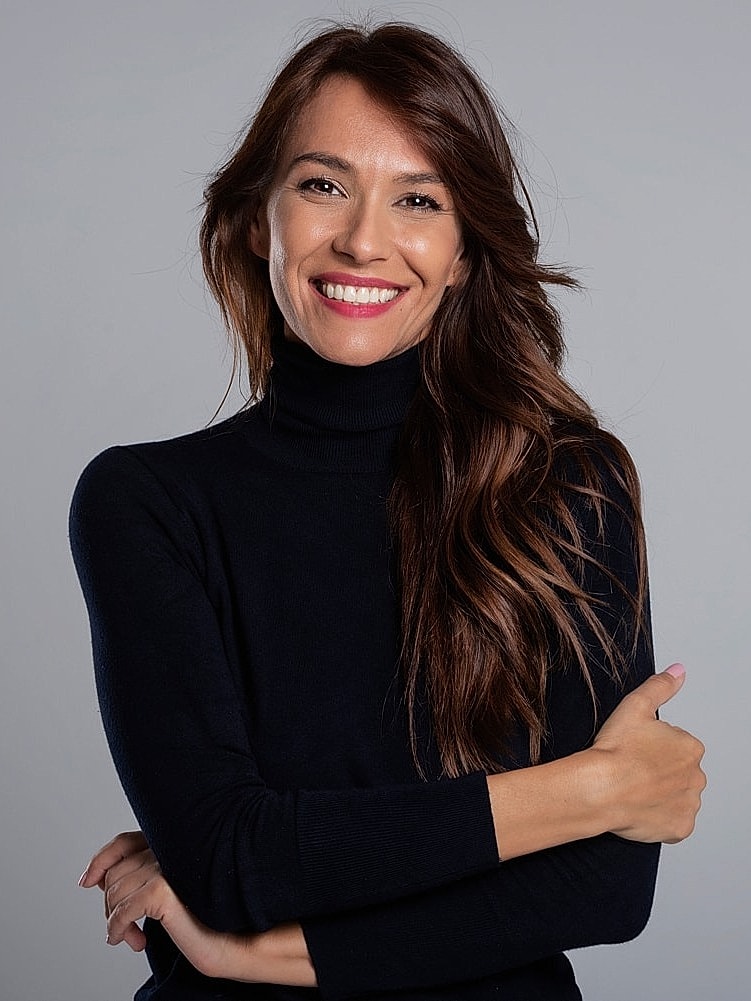 Smiling woman in black turtleneck portrait.