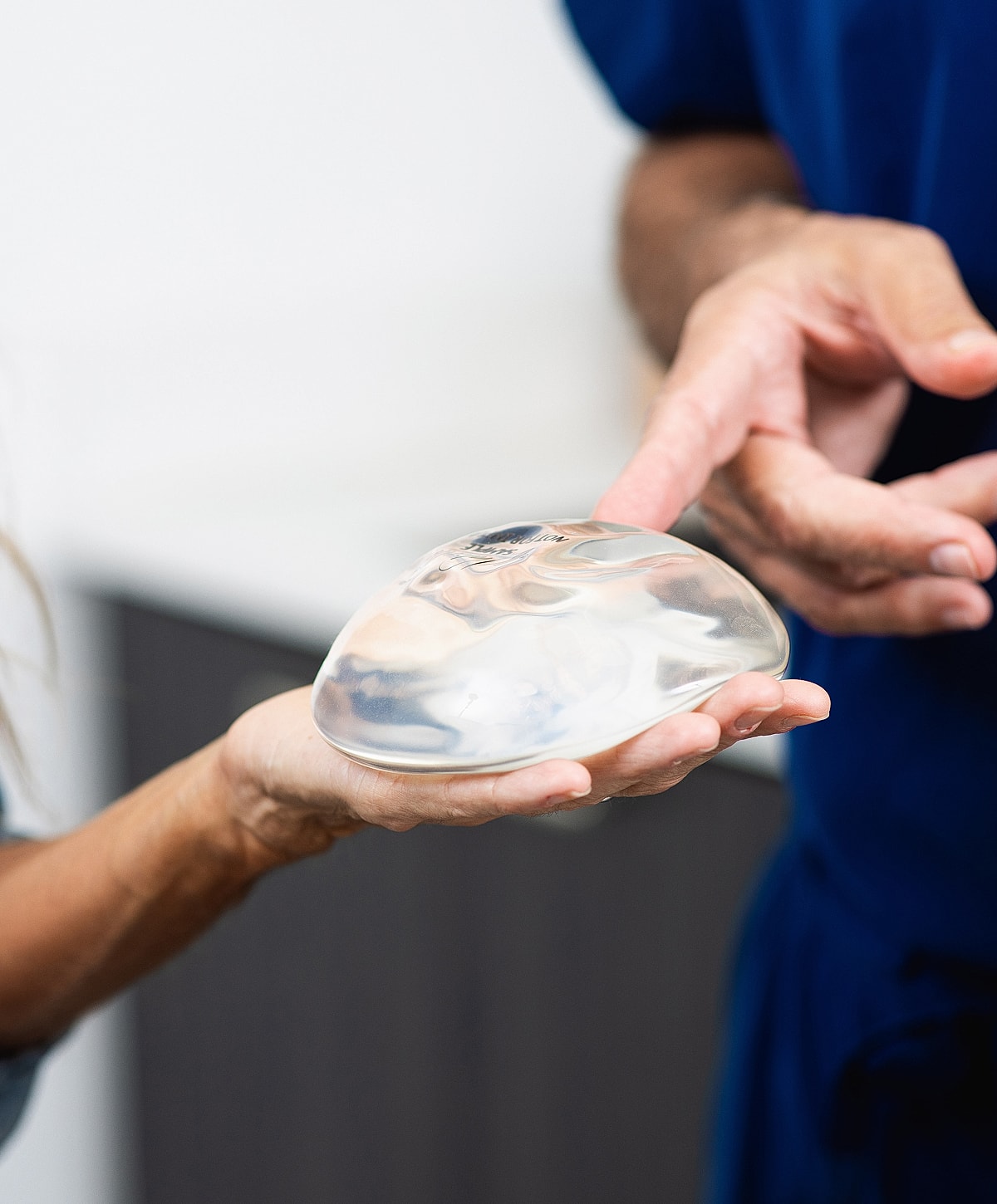 Patient holding silicone breast implant at consultation.