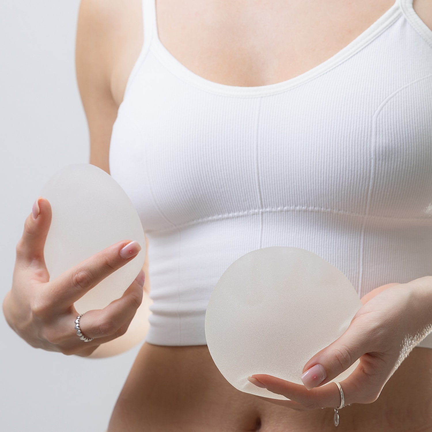 Woman holding silicone breast implants.