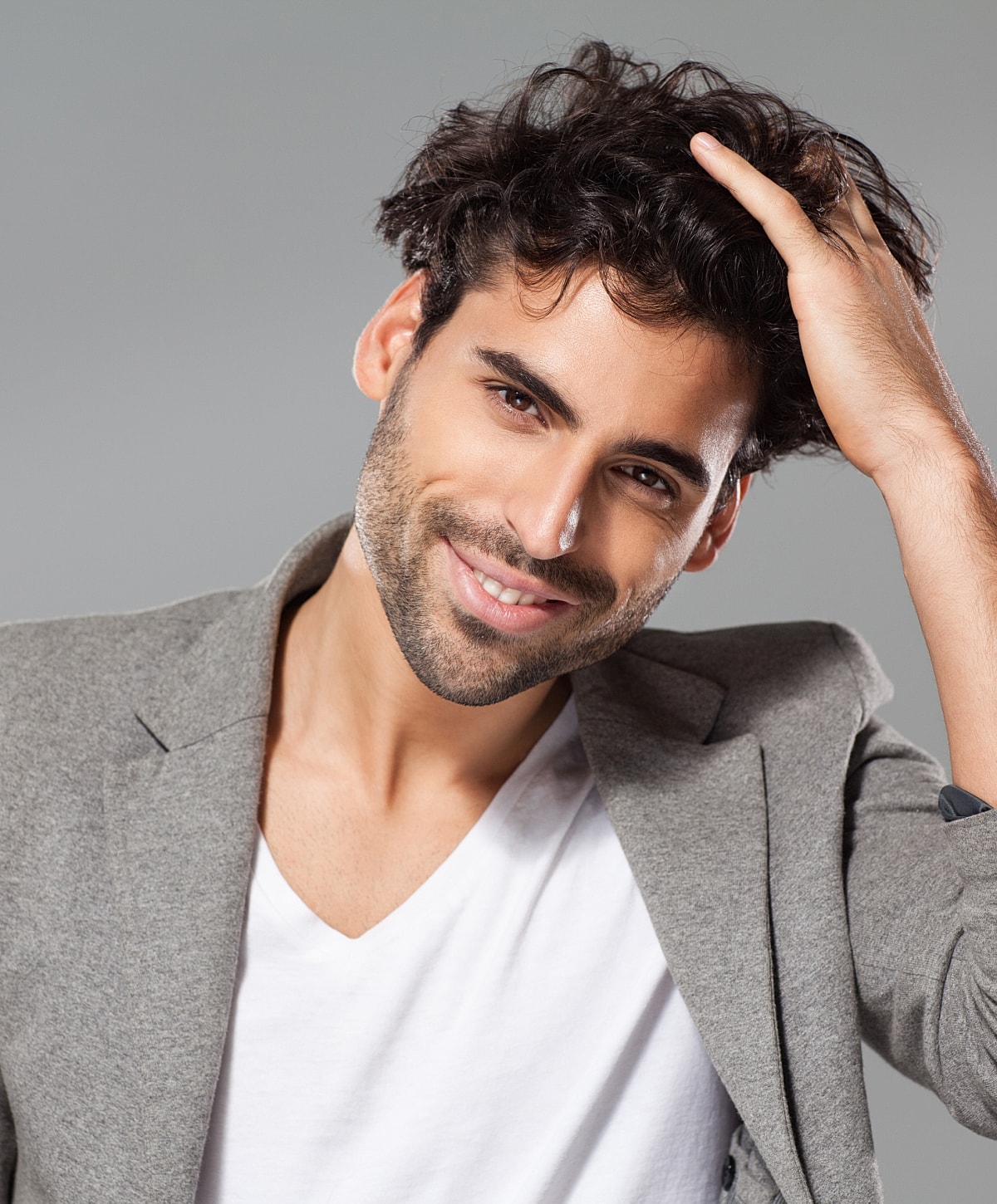 Smiling man with curly hair in casual outfit.