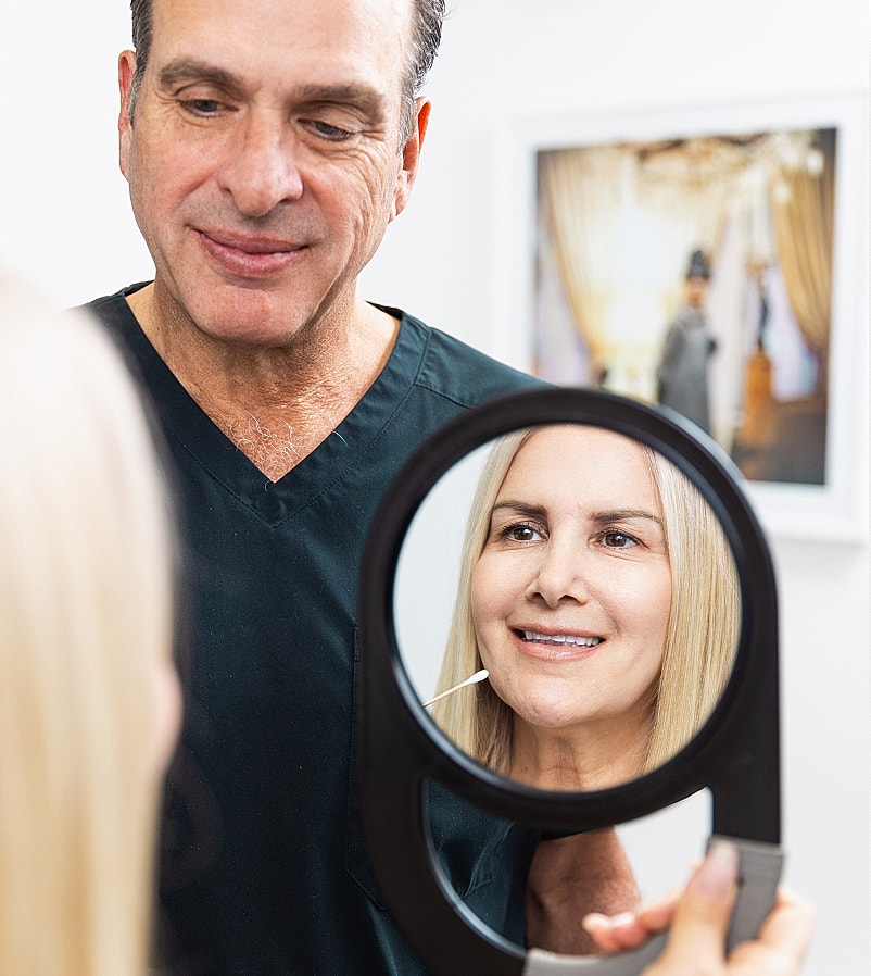 Dentist showing patient her smile in mirror.