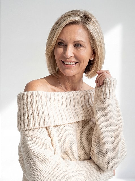 Smiling woman in off-shoulder sweater.