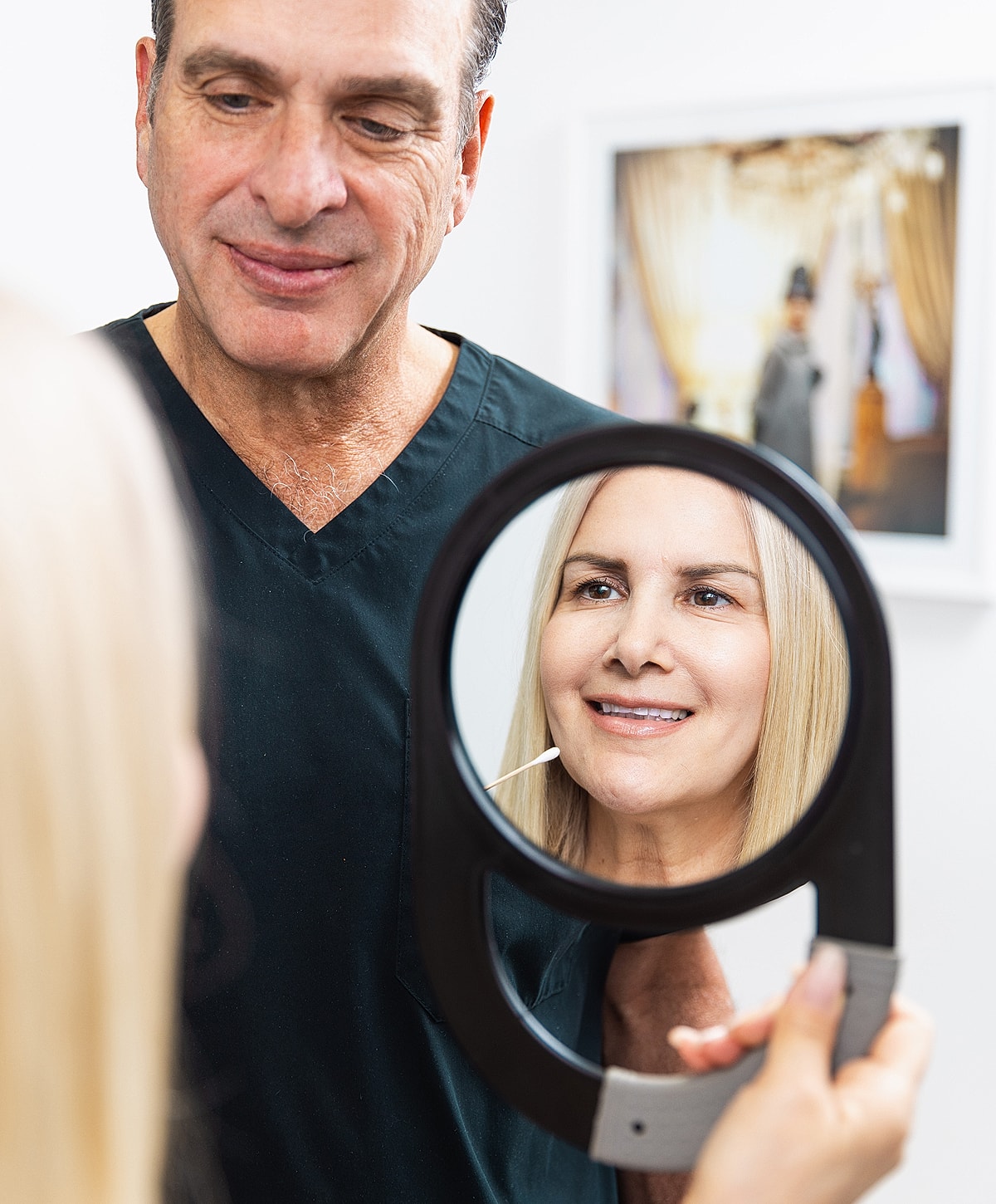 Dentist assisting patient in mirror reflection.