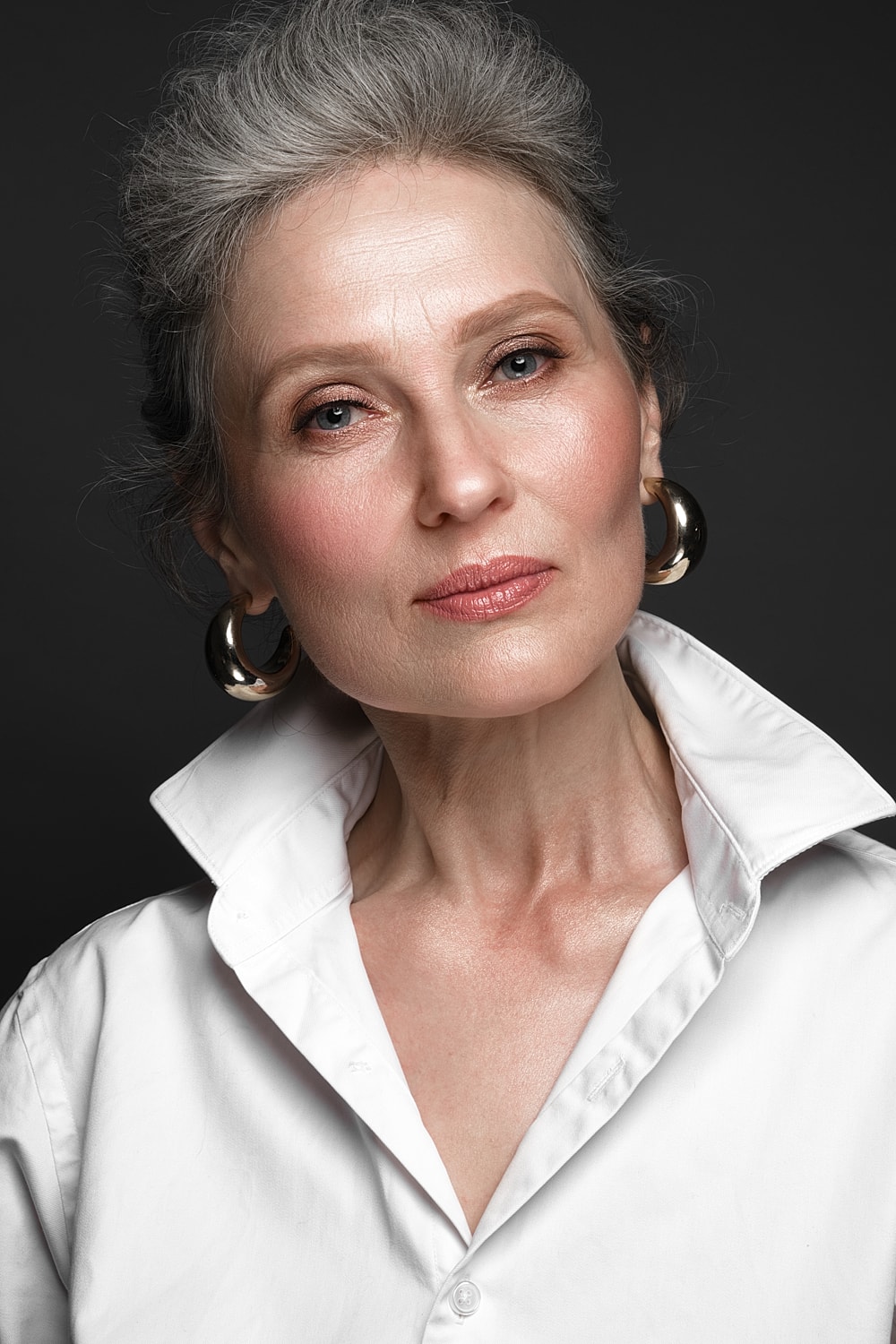 Older woman in white shirt, elegant pose.