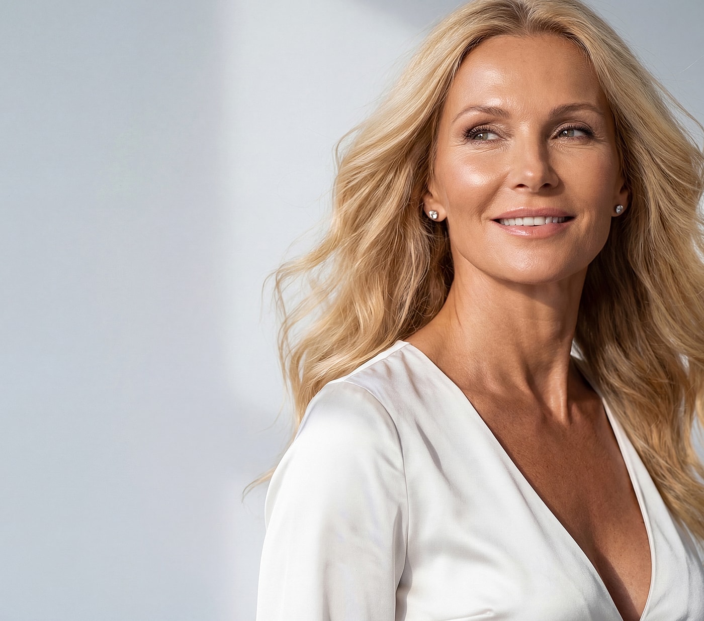 Smiling woman with blonde hair in soft lighting.