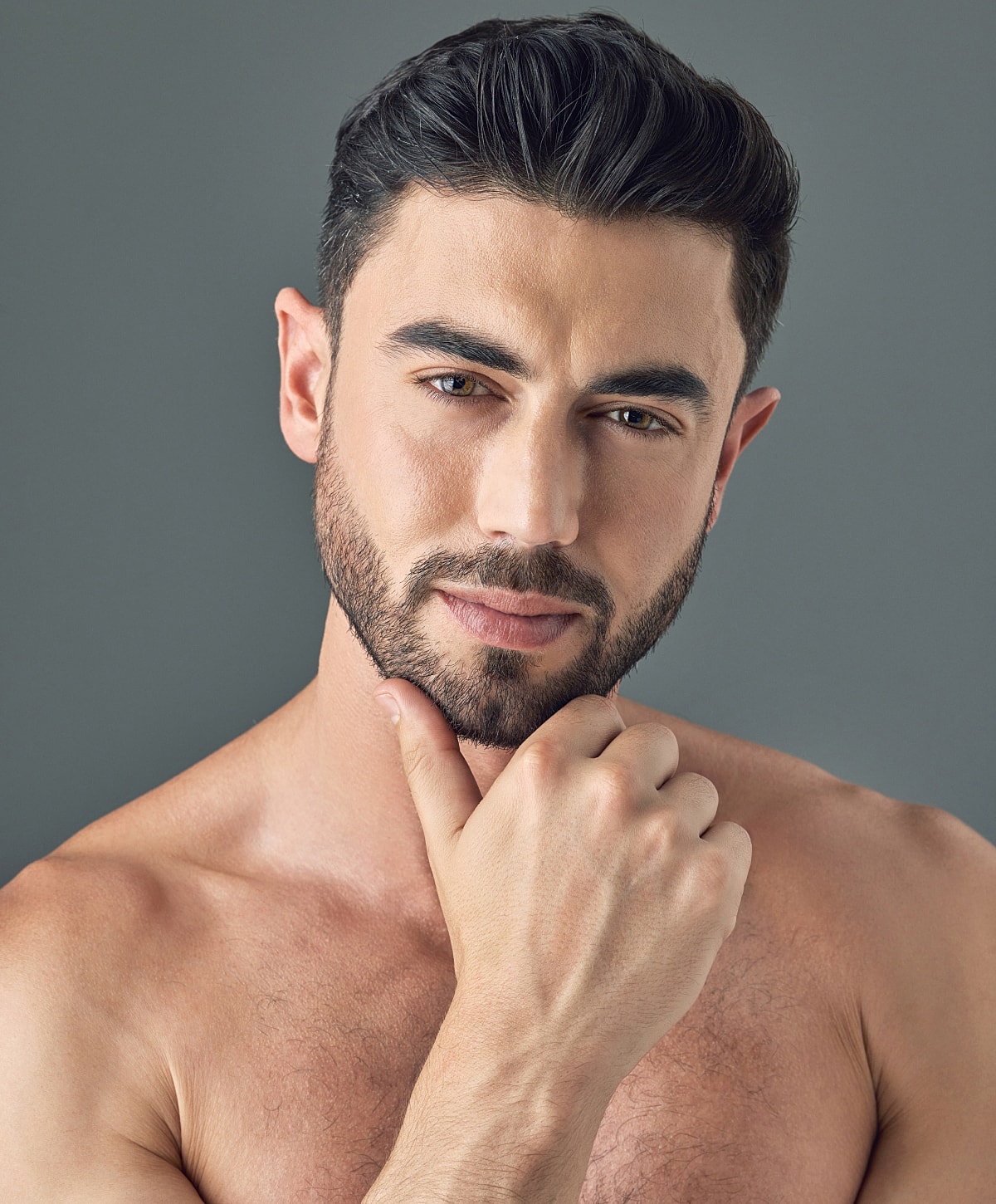 Male model with thoughtful expression against gray background.