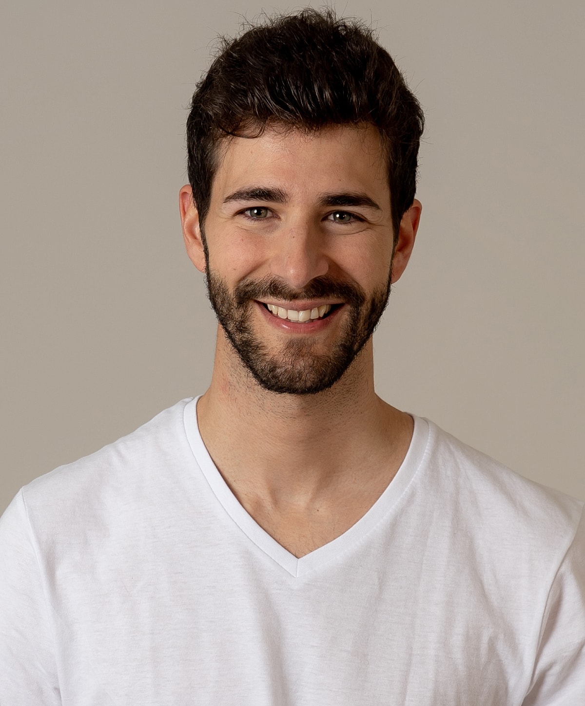 Smiling man wearing a white V-neck shirt.