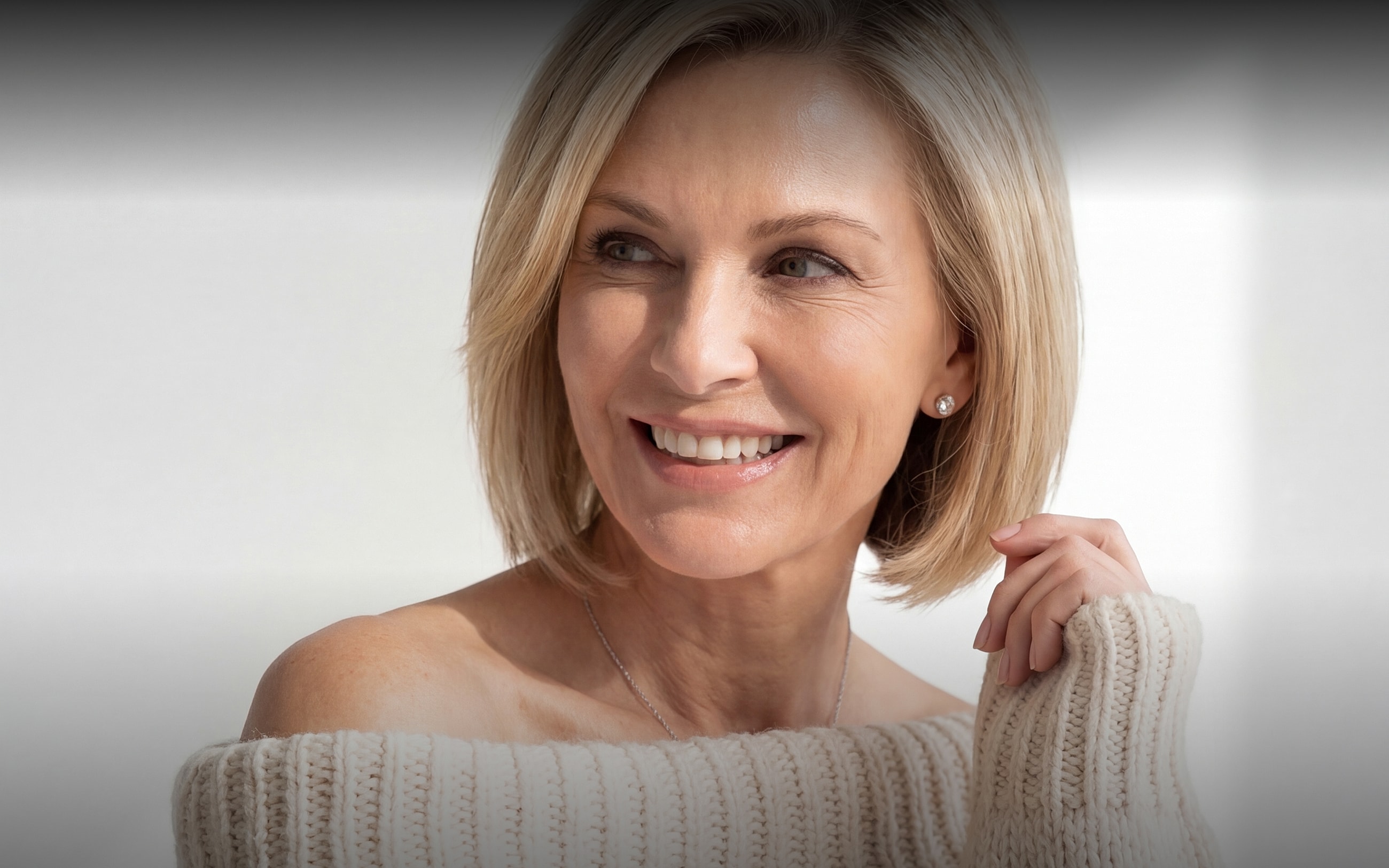Smiling woman in soft sweater, natural lighting.