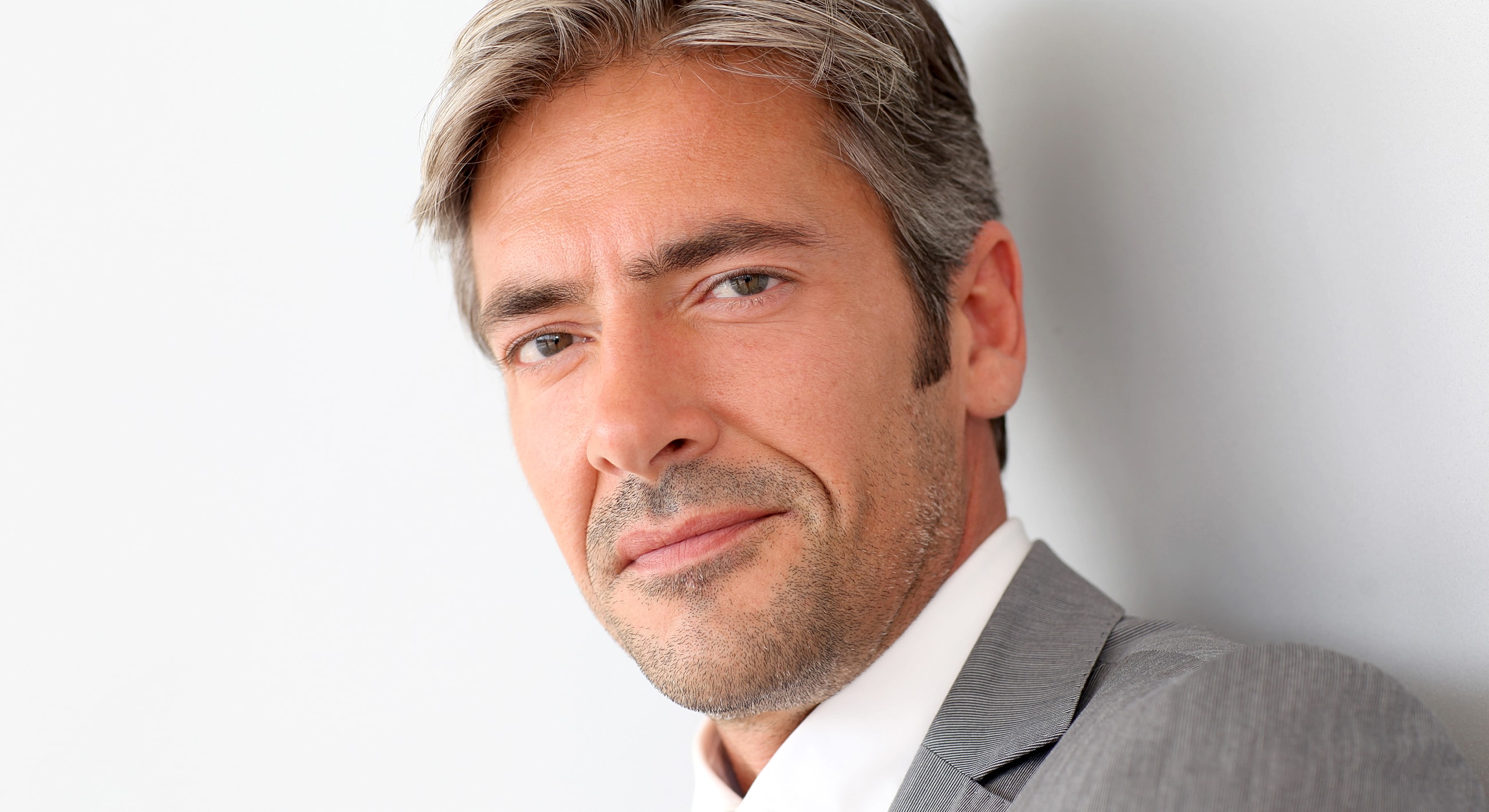 Man in gray suit against white background.