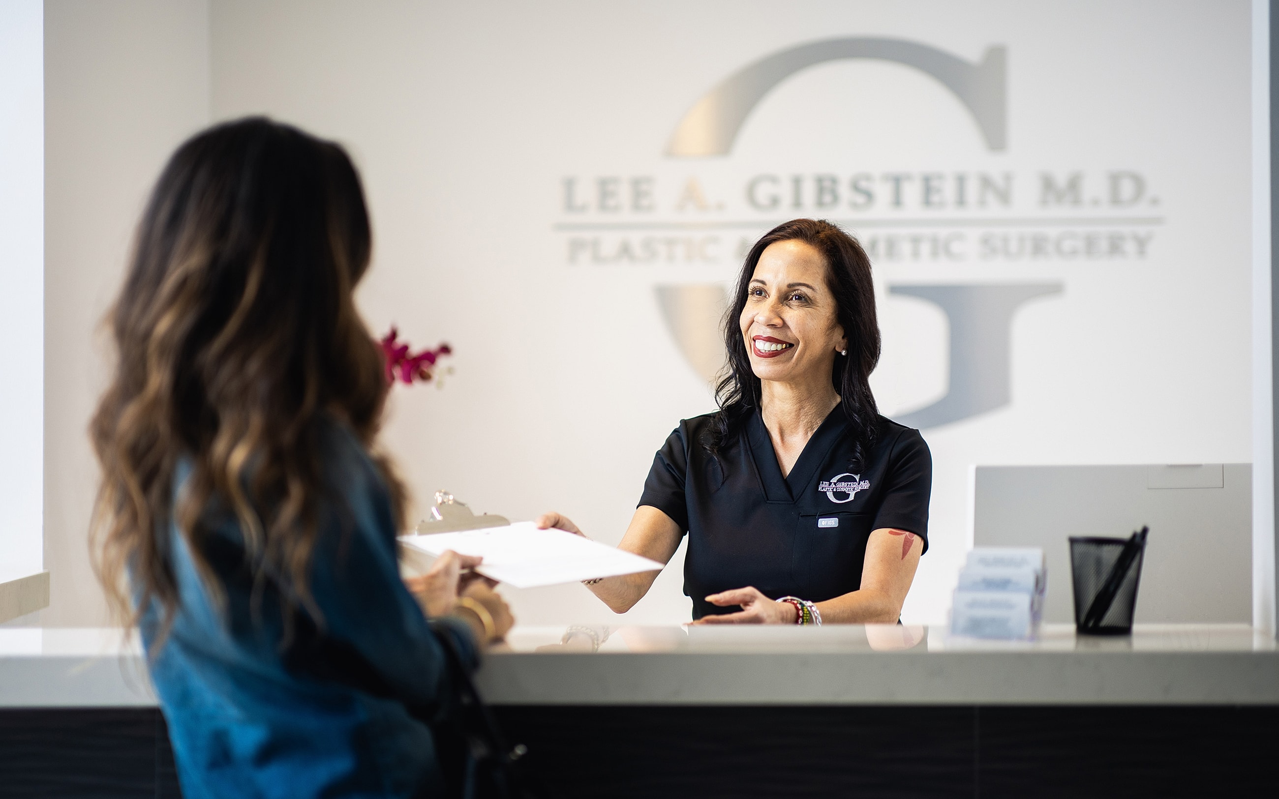 Receptionist assisting a client at plastic surgery office.