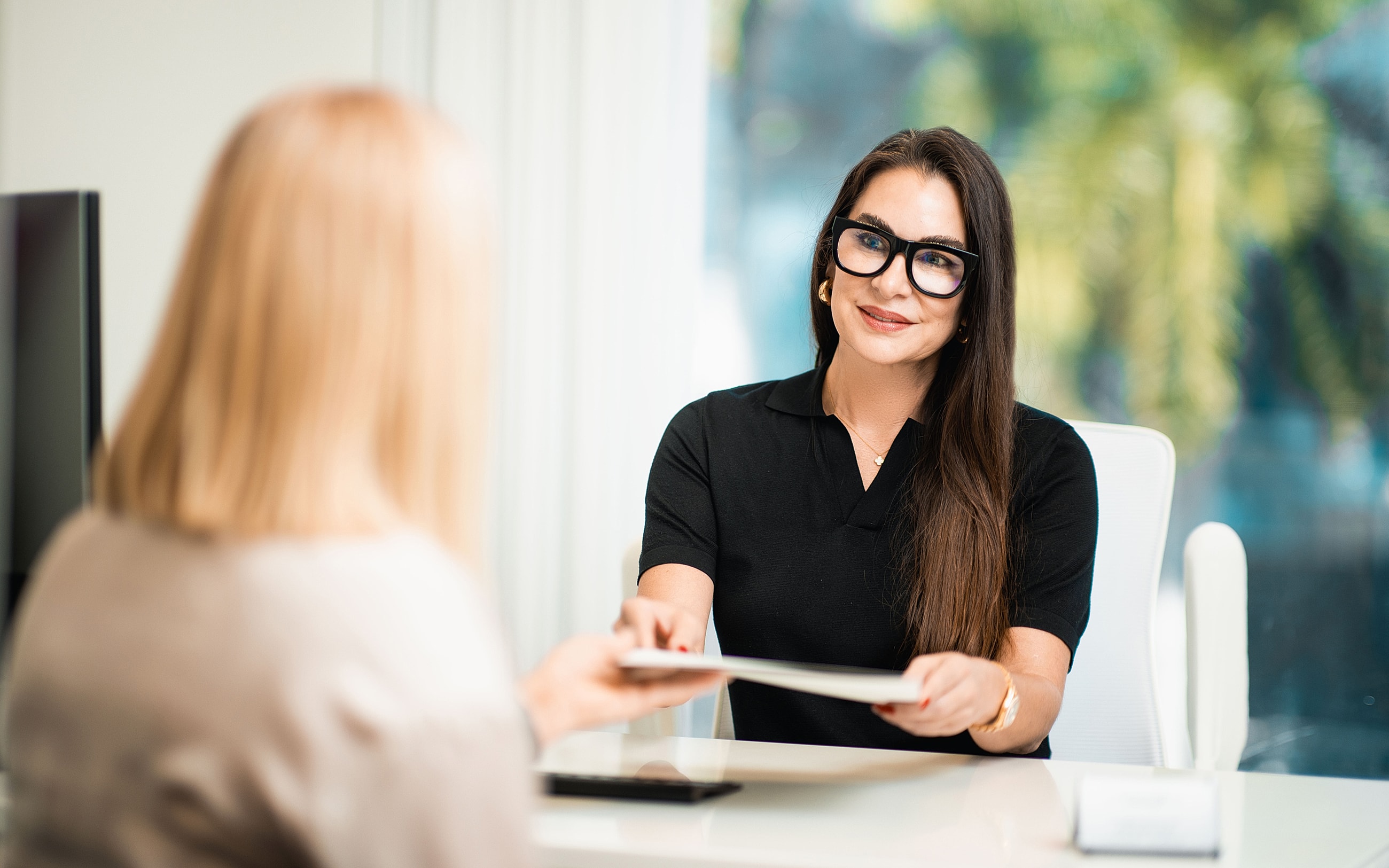 Woman handing document to another person.